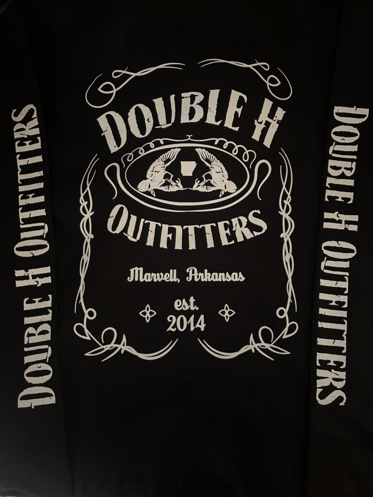 Black shirt printed with a Double H Outfitters label design reading Marvell, Arkansas, est. 2014, with Double H Outfitters down both sleeves