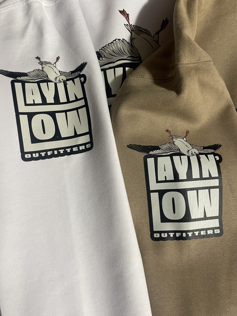 White and tan hoodies printed with the stacked Layin' Low Outfitters logo