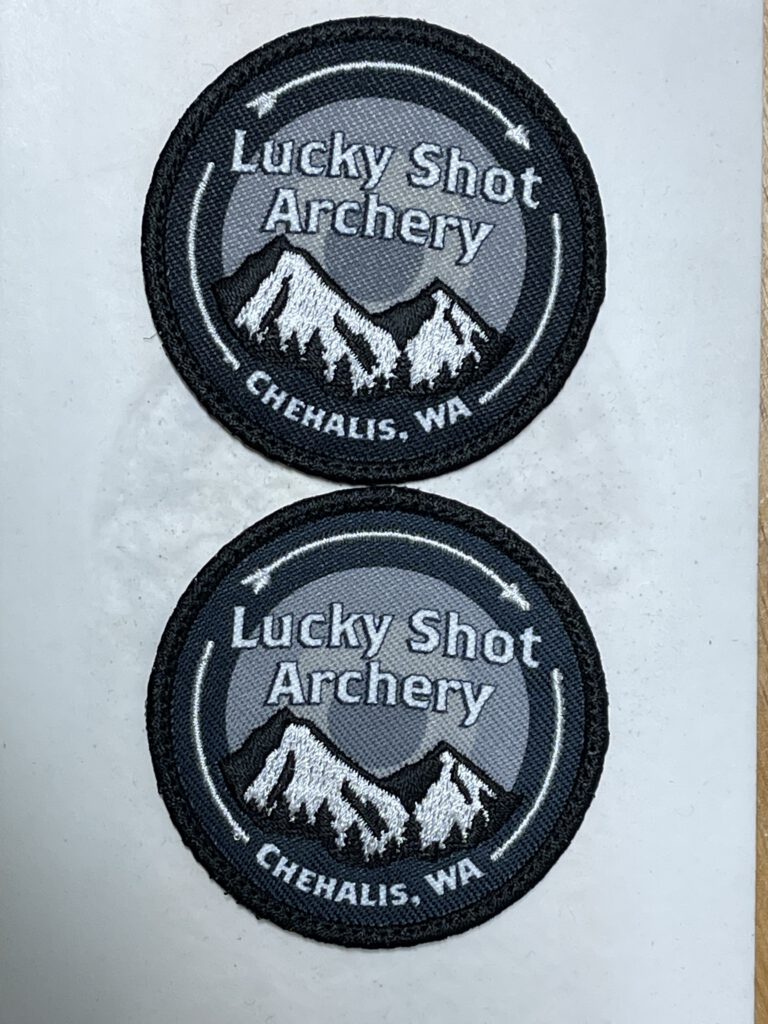 Two round Lucky Shot Archery patches in black, gray and white, with mountains, an arrow and Chehalis, WA