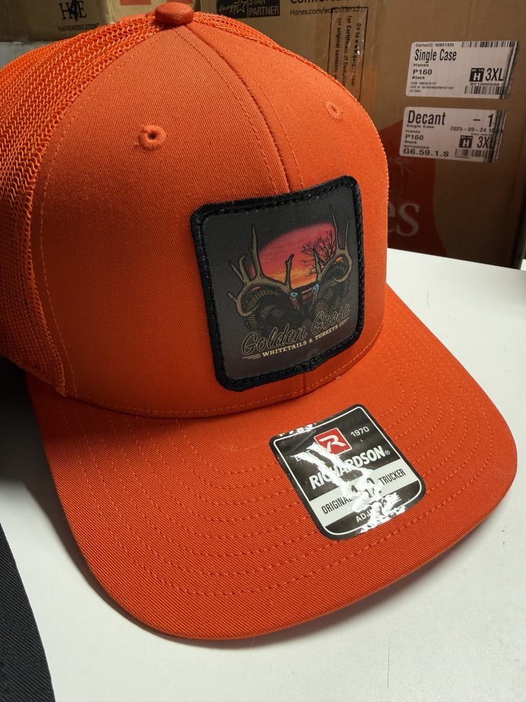 Orange trucker hat with a full-color Golden Goose Whitetails & Turkeys patch, antlers against a red sunset, edged in black stitching