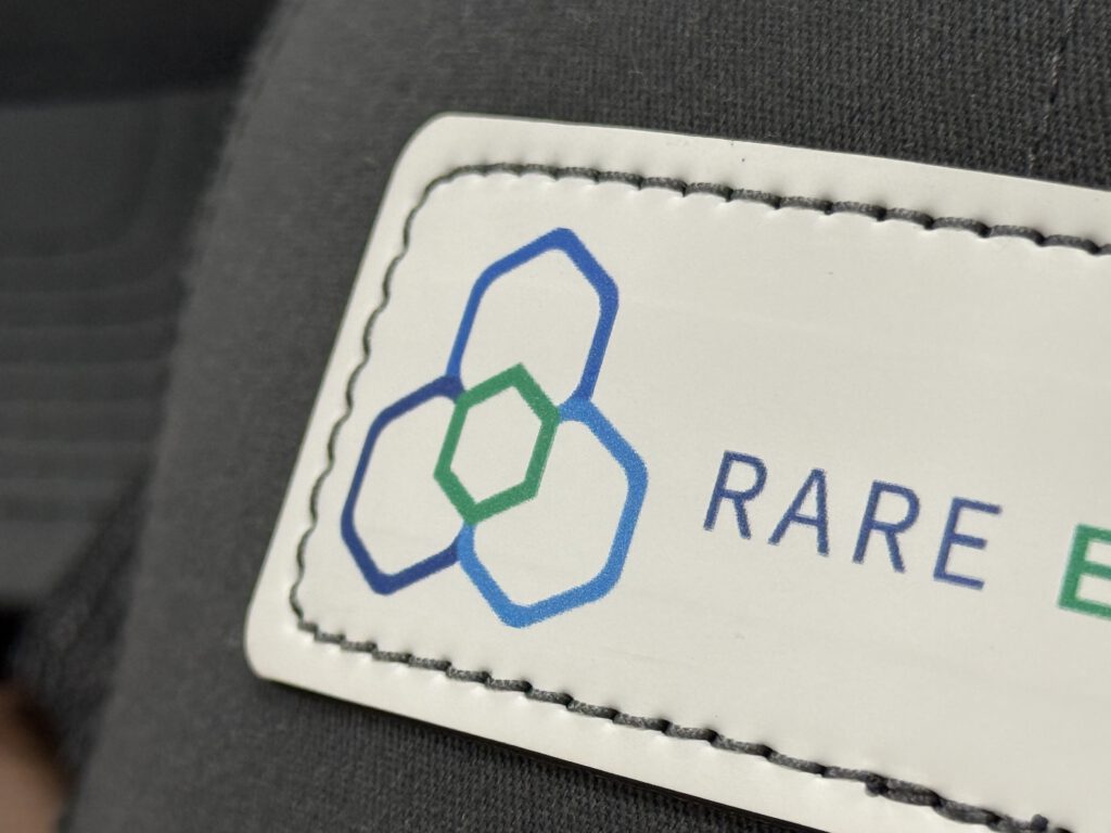 Close-up of the printed Rare Earth Salts hexagon logo and stitched edge on a white hat patch