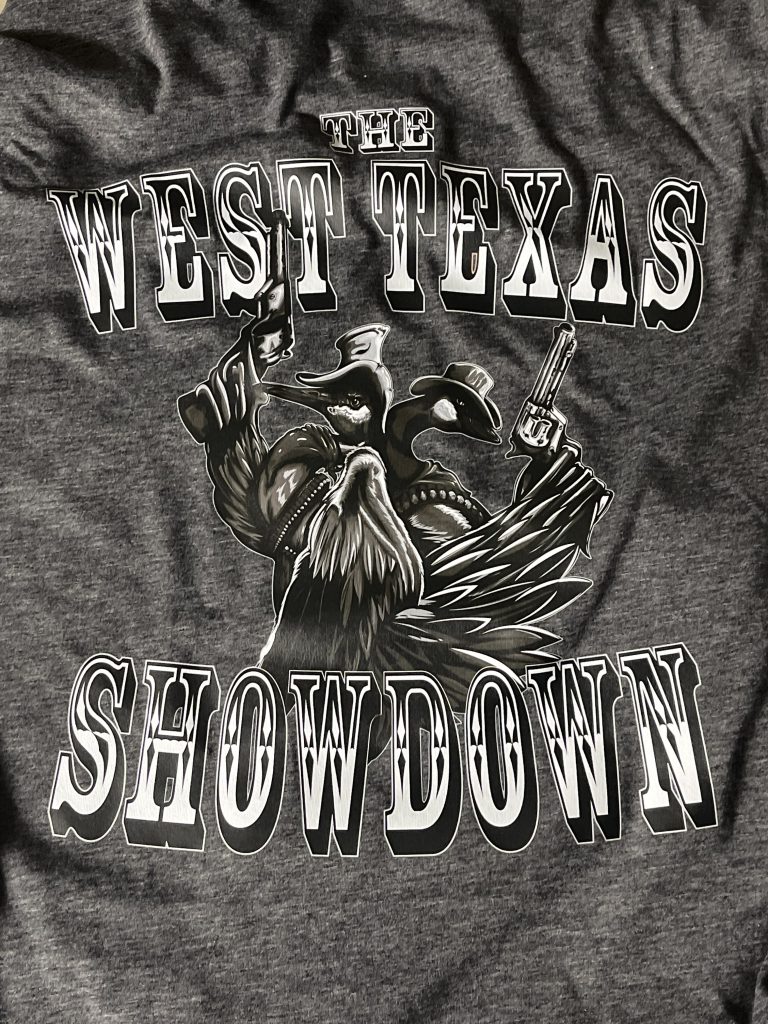 Charcoal tee printed with The West Texas Showdown: a crane and a goose in cowboy hats, back to back with revolvers drawn