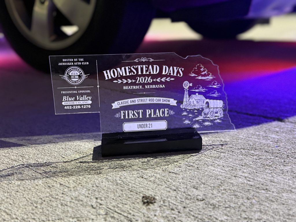 Clear acrylic Homestead Days 2026 First Place award cut in the shape of Nebraska, with a homestead, windmill and covered wagon, on a black base